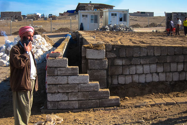 A member of the Yazidi construction team takes a smoke break from building the foundation of the new health centre in Domiz Refugee Camp