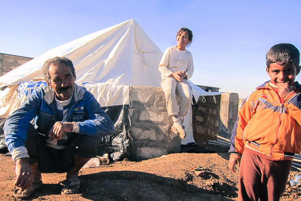 A father with his children taking a break from setting up his new tent on a cement base in Domiz Refugee Camp, November 2012